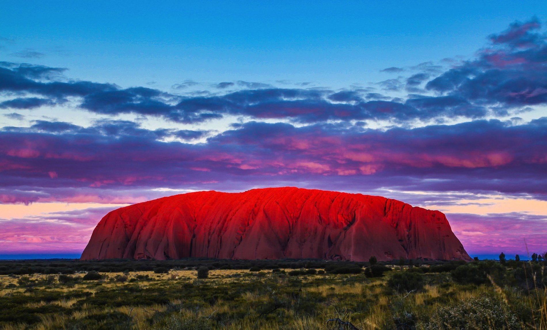 Uluru glowing at sunset in the heart of the Australian Outback, a sacred monolith radiating ancestral energy and spiritual power.