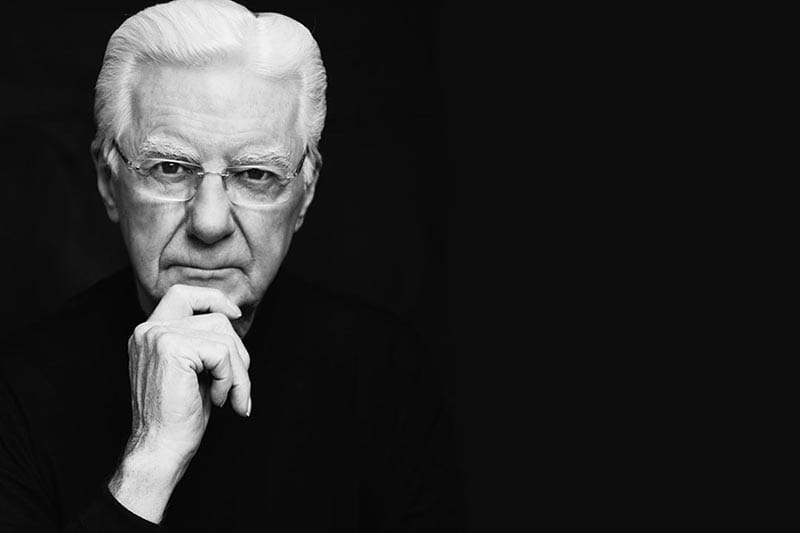 Black and white portrait of Bob Proctor in a suit, symbolizing his timeless influence in the world of personal development