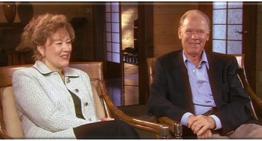Esther and Jerry Hicks side-by-side, smiling during an interview in a cozy, wood-paneled room with shoji doors