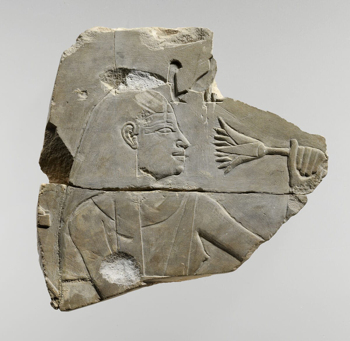 Ancient Egyptian wall relief depicting a figure smelling a lotus flower