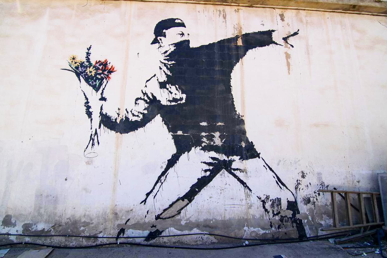 Banksy Love Is in the Air Flower Thrower mural symbolizing non-attachment and peace over force