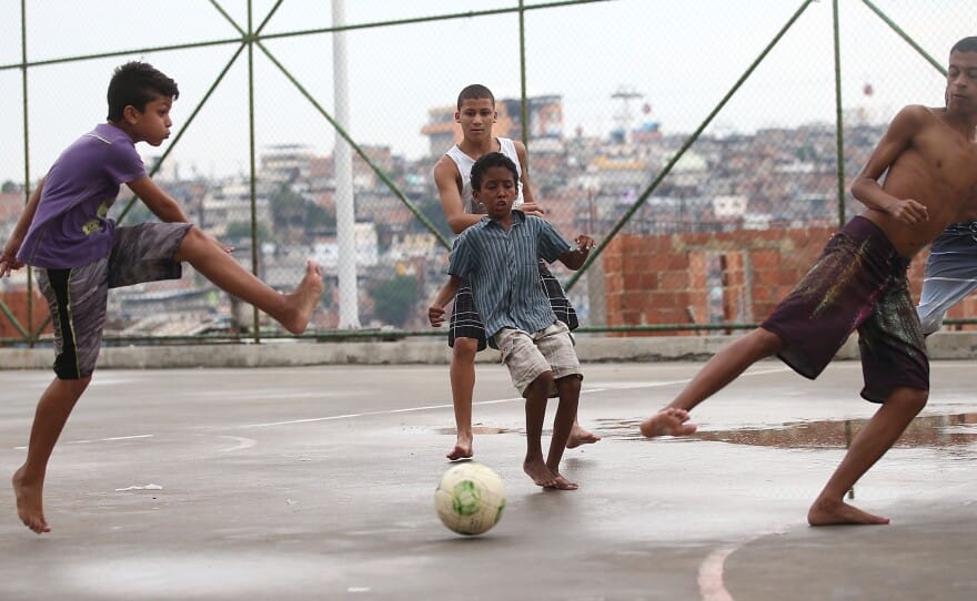 Children playing barefoot street football in Brazil, expressing imagination, joy, and creative freedom through play.