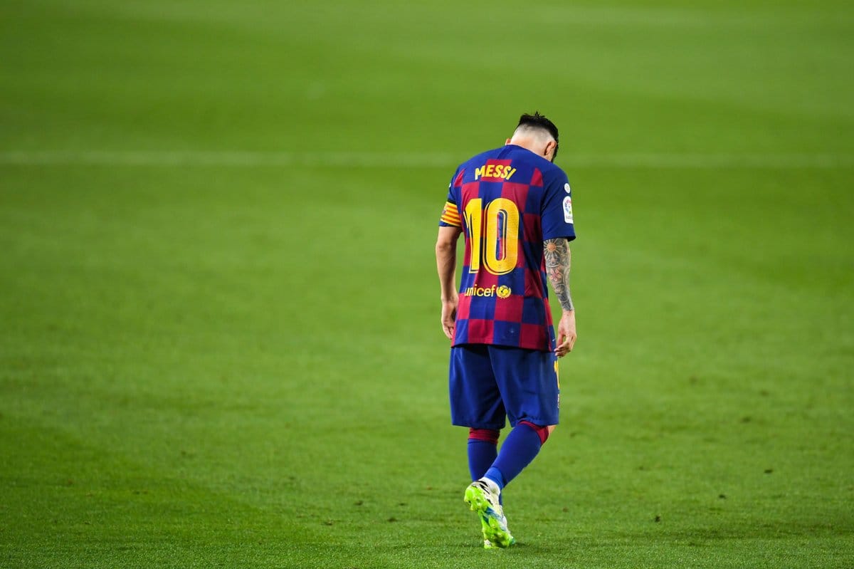 Lionel Messi walking alone on the pitch, head lowered in quiet reflection after defeat.