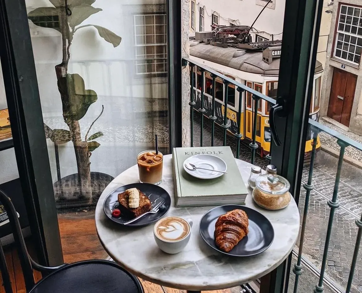 Lisbon café table with coffee and pastries overlooking a yellow tram