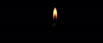 Single candle flame glowing in darkness, symbolizing stillness, focus, and inward awareness