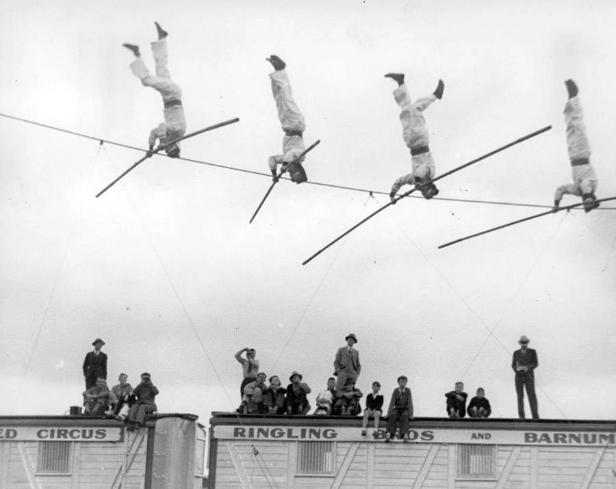 Early 20th-century circus acrobats performing headstands on a tightrope, symbolizing risk, discipline, and physical mastery