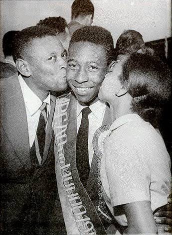 Young Pelé smiling as family members kiss him in celebration, reflecting love, support, and early belief before global fame