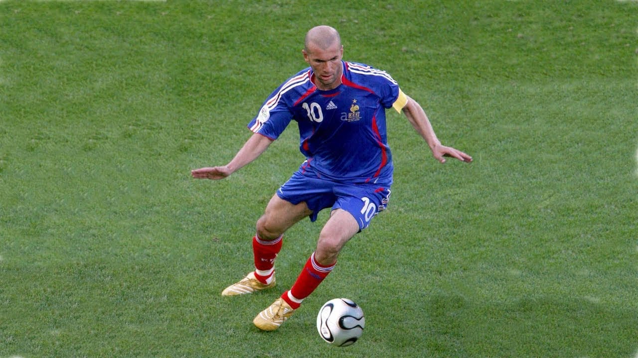Zinedine Zidane calmly controlling the ball under pressure, demonstrating composure, balance, and presence during a football match.