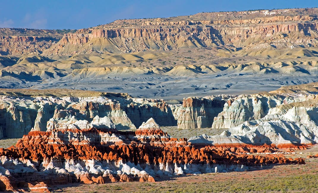 Photograph of Coal Mine Canyon on the Navajo Nation near Tuba City, Arizona, showing layered, multicolored rock formations carved by erosion across a vast desert landscape.