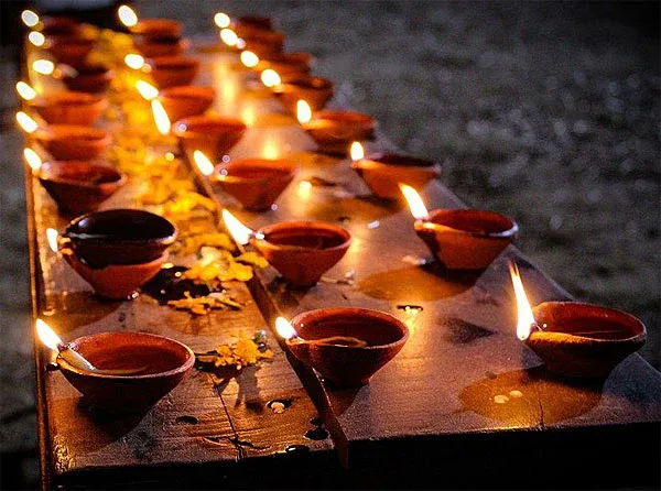 Row of lit diya lamps during Lakshmi Puja ritual in a Hindu temple