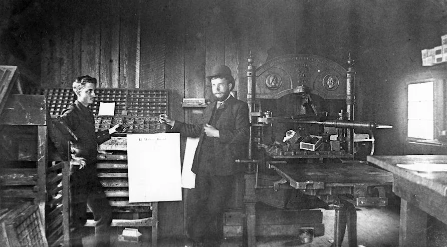 Men working inside a late nineteenth-century industrial shop, reflecting motion, self-invention, and ambition forming without proof or structure.