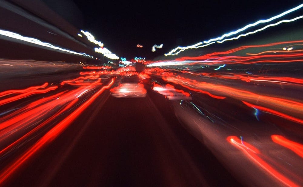 Blurred light trails rushing through darkness, symbolizing unchecked acceleration and the loss of inner coherence.