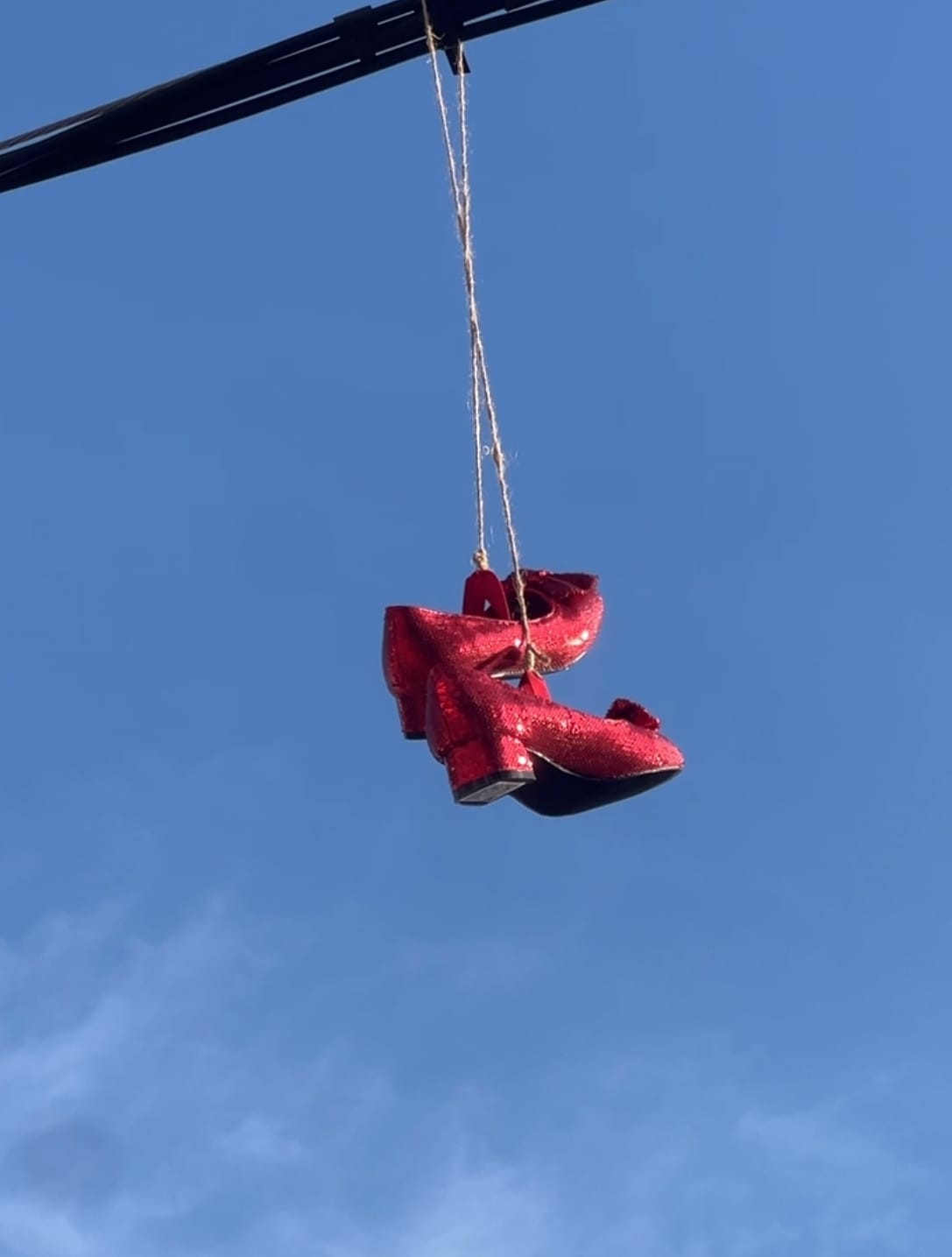 Red shoes hanging from a power line, part of the Follow the Red Shoes street art project and Messages from the Universe QR installation.