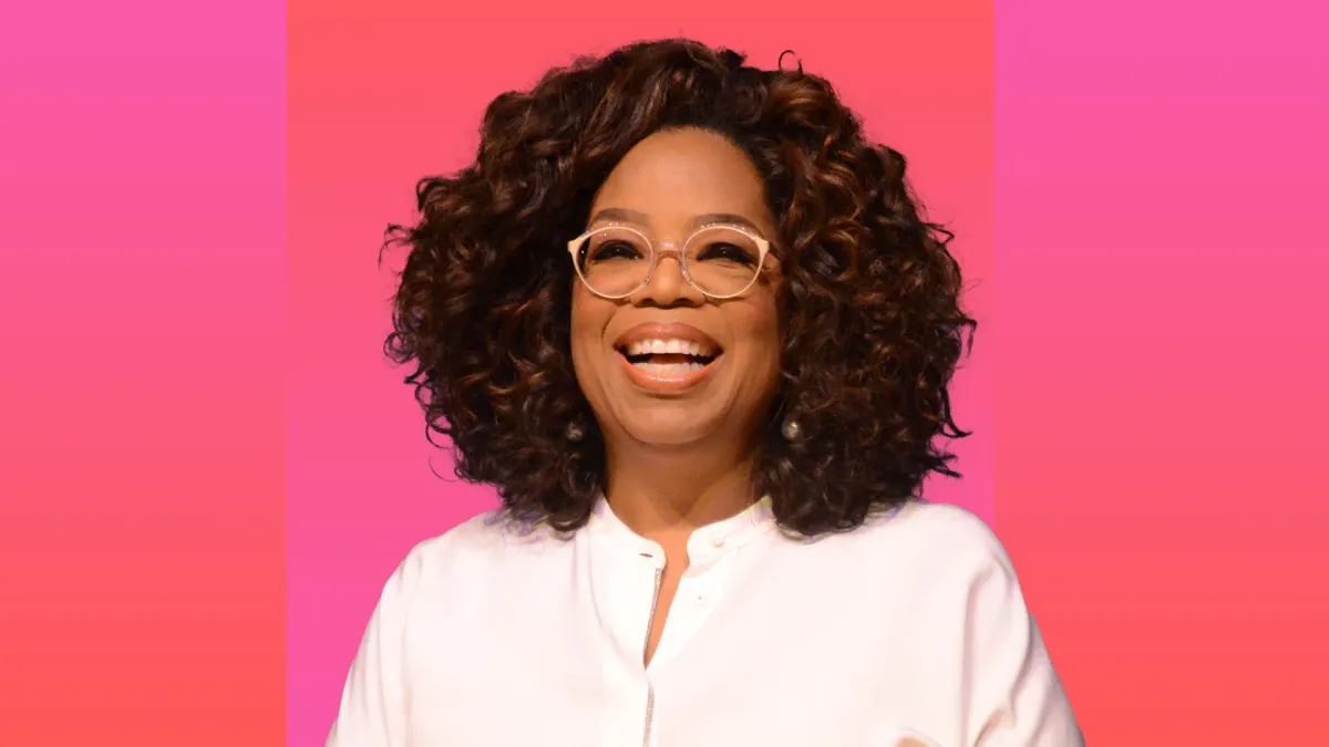Oprah Winfrey smiling against a pink gradient background — manifestation, intention, and Law of Attraction teachings
