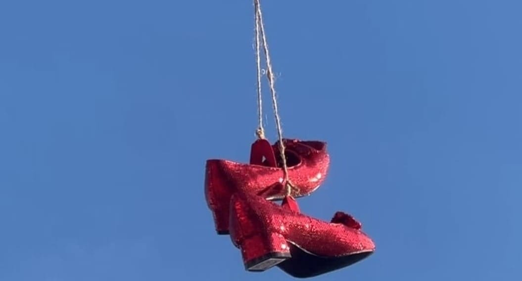 Red shoes hanging from power lines against a blue sky, symbolizing messages from the universe and synchronicity.