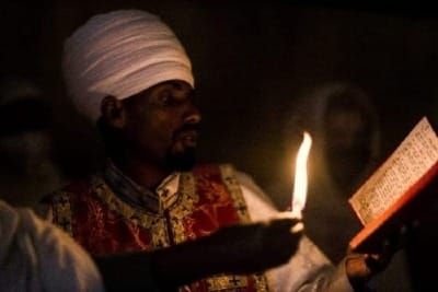 Mystical photo of a man in a red turban reading a book by candlelight, evoking Neville Goddard’s mentor Abdullah.