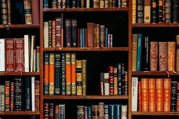 Stack of old library books symbolizing Neville Goddard’s timeless teachings in The Ultimate Guide to manifestation.