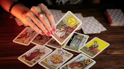 Close-up of a hand holding a tarot card during an online psychic reading