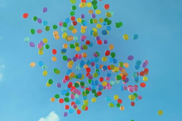 Colorful balloons floating freely in the open sky symbolizing the law of non-attachment, letting go, emotional freedom, and effortless manifestation